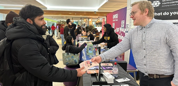 A man handing another man a leaflet.