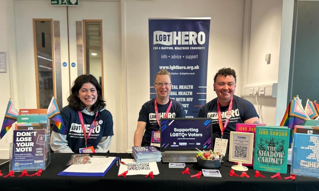 Three people sitting at an information desk for LGBTQ+ voters