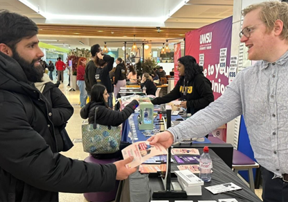 A man handing another man a leaflet.