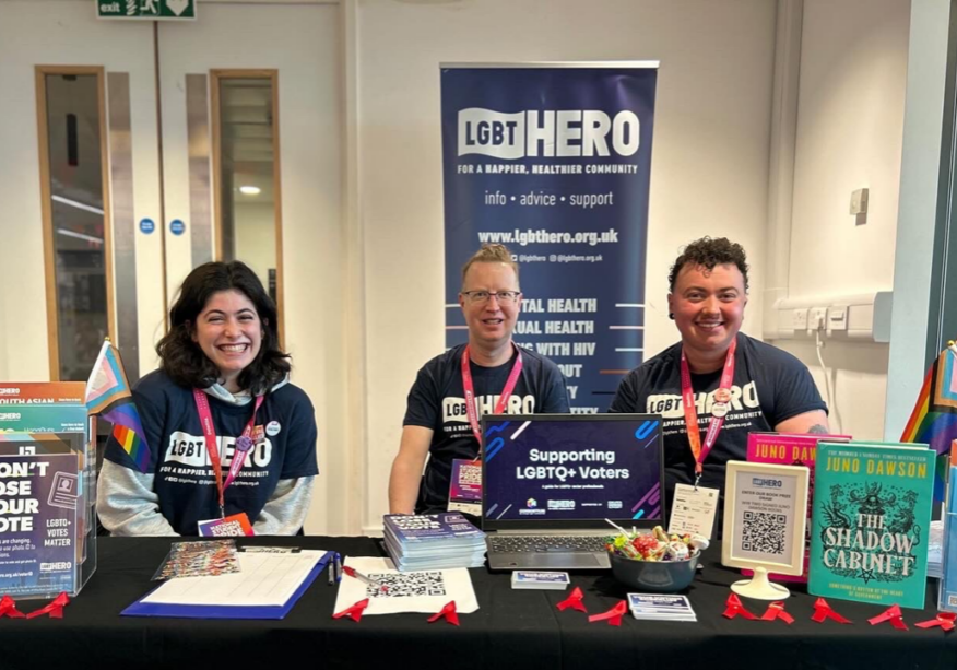 Three people sitting at an information desk for LGBTQ+ voters