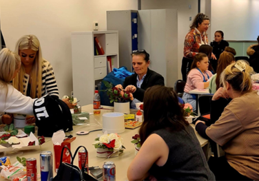 A group of people sitting across two tables engaged in a floral arrangement activity.